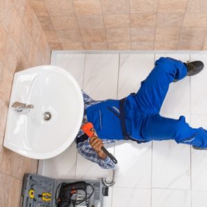 High Angle View Of Male Plumber Repairing Sink In Bathroom