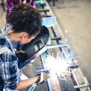 A mixed race adult woman working in a metal workshop